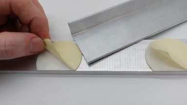 Doppelseitige Klebeetiketten werden an Metallteilen angebracht